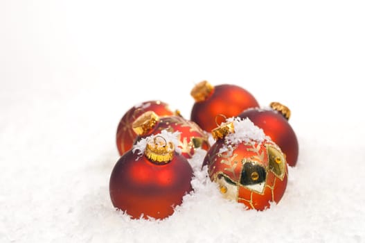 Red Christmas baubles on snow with gold decorations
