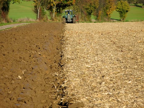 Tractor ploughs brown field in Kraichgau,Germany. Filling the format. Landscape.
