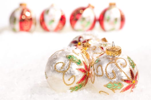 White glass baubles and a line of colorful baubles in the background on snow