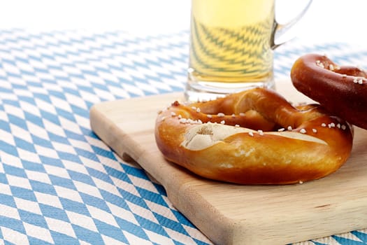 Two pretzels with a glass of beer on the Bavarian flag