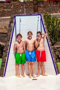 cute boys have fun unter the pool shower