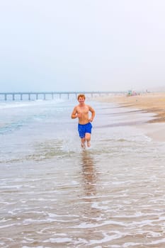 attractive young boy jogging at the beach