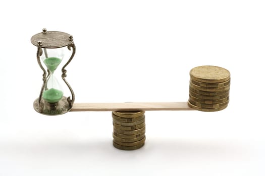 "Time is money"" concept. An hourglass in the balance with several dollar coins."