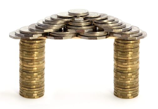 House or gateway made of coins over white background. Concepts of wealth, riches, dream house, investment.