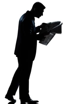 one caucasian man walking reading newspaper  full length silhouette in studio isolated white background