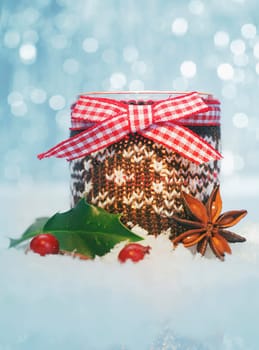 Country Christmas decoration still life with holly and spice in snow against a sparkling bokeh of party lights
