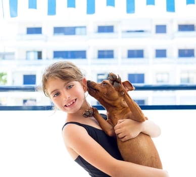 Brunette kid girl with summer swimsuit playing with dog in apartment