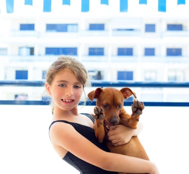 Brunette kid girl with summer swimsuit playing with dog in apartment