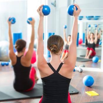 Pilates toning ball in women fitness class rear mirror view