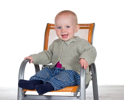 Happy smiling baby sitting alone in a stylish modern childs highchair with copyspace