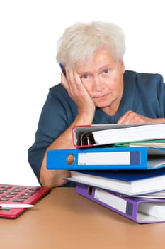Exhausted senior lady leaning on her elbow with a dejected look alongside a huge stack of files and paperwork