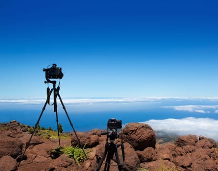 Landscape photographer tripods and cameras over high mountain over clouds