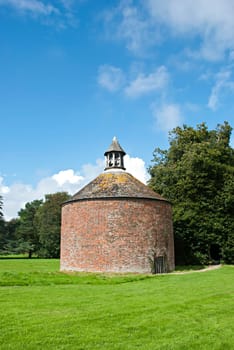 A vintage brick Dovecote under a blue sky