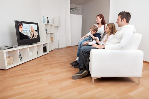Young family watching TV together at home