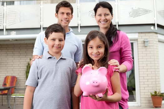 Portrait of cute little girl holding a piggy bank with her family