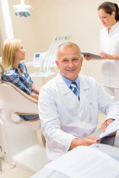 Portrait of mature dentist surgeon at dental office with patient