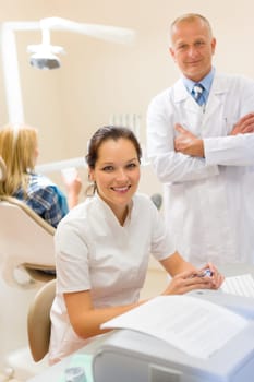 Dentist with assistant smiling at stomatology office professional health care