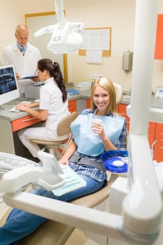 Happy female patient at dental surgery dentist with assistant