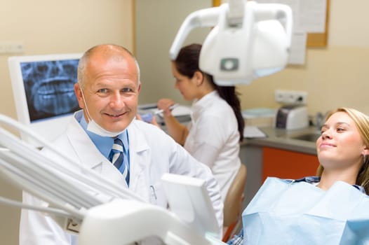 Friendly dentist with female patient regular visit at dental surgery