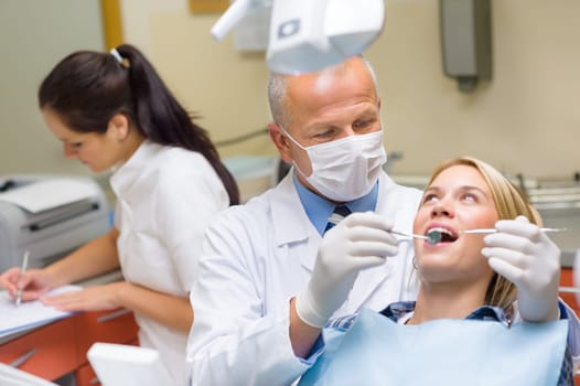 Professional dentist doing teeth checkup on female patient dental surgery