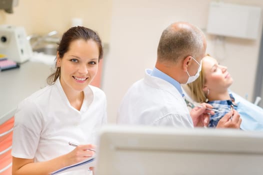 Smiling dental nurse prepare patient documentation stomatology clinic