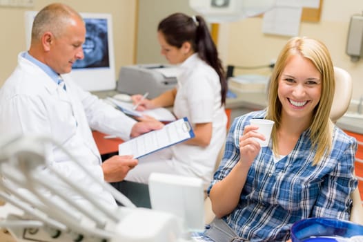 Woman beautiful smile at dental surgery male dentist check documents