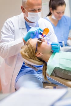 Young woman having teeth check-up in stomatology clinic male dentist