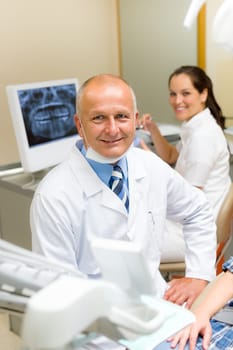 Professional dental surgeon sitting in office with assistant nurse