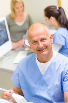 Professional dental surgeon sitting in office with assistant nurse