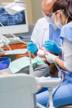 Woman at dentist surgery having dental checkup professional medical team