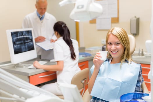 Dental surgery smiling female patient dentist consulting with assistant nurse