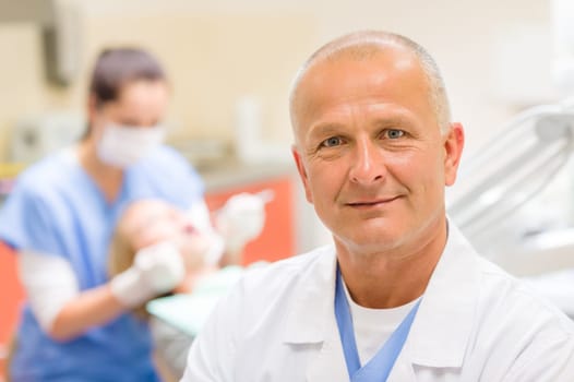 Portrait of mature dentist surgeon posing at office