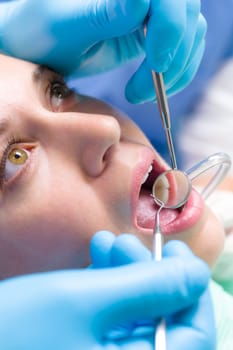 Dentist surgery closeup of woman's open mouth with dental tools