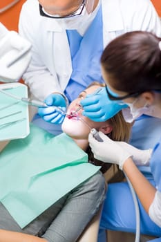 Professional dentist and nurse doing operation on female patient