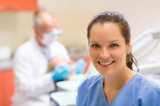 Female dental assistant smiling at stomatology office dentist with patient