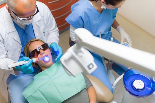 Young woman patient have dental surgery dentist use UV lamp