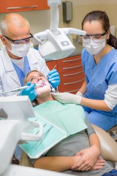 Professional dentist and nurse doing dental treatment on female patient