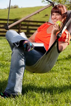 A college student is studying outside in the backyard.