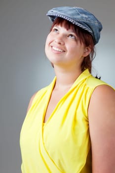 Portrait of a happy girl in yellow blouse and a denim cap