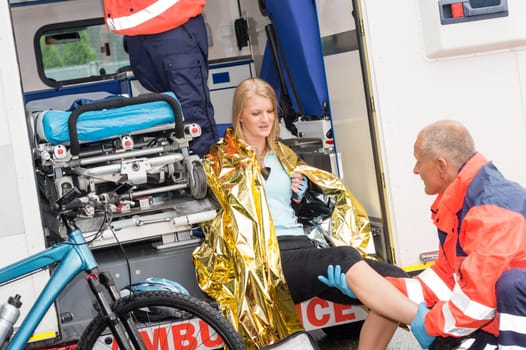 Emergency paramedics with woman bike accident in ambulance help injury