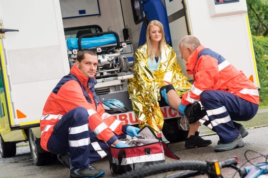 Bike accident woman emergency doctor checking leg in ambulance