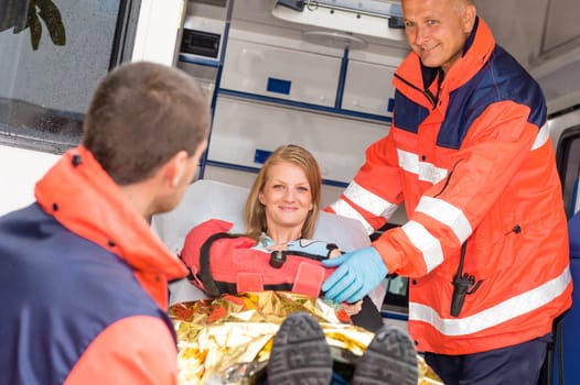 Paramedics helping woman in ambulance broken arm smiling accident victim