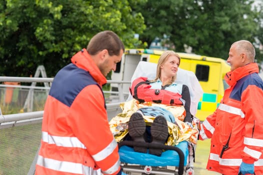 Patient talking with paramedics after accident aid emergency arm injury