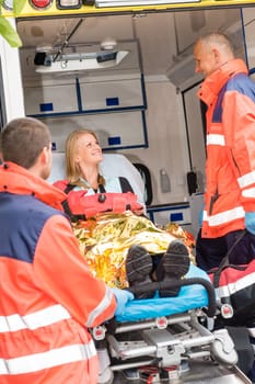 Emergency paramedics with injured woman in ambulance on stretcher
