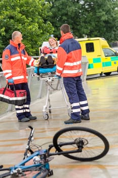 Bike accident paramedics with woman on emergency stretcher ambulance aid