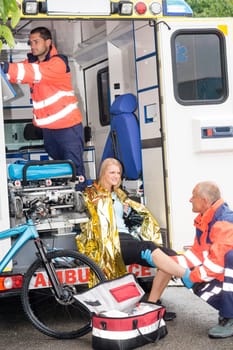 Emergency paramedics with woman bike accident in ambulance help injury