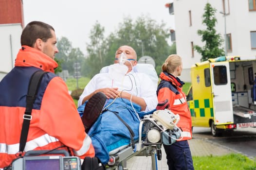 Paramedics with patient on emergency stretcher ambulance aid woman man