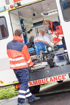 Paramedics putting patient man oxygen mask in ambulance car