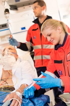 Paramedics injecting sick patient in ambulance heart attack aid emergency