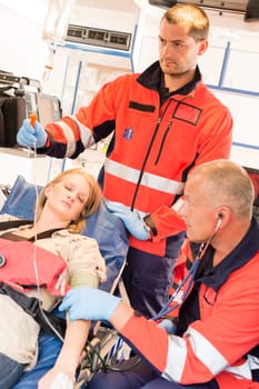 Unconscious patient woman emergency ambulance paramedics measuring blood pressure